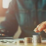 مردی که درحال حساب کتاب با ماشینحساب است و با دست راست سکهها را دستهبندی میکند.