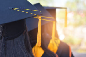 چند شخص که لباس فارغالتحصیلی پوشیده و در صف ایستادهاند